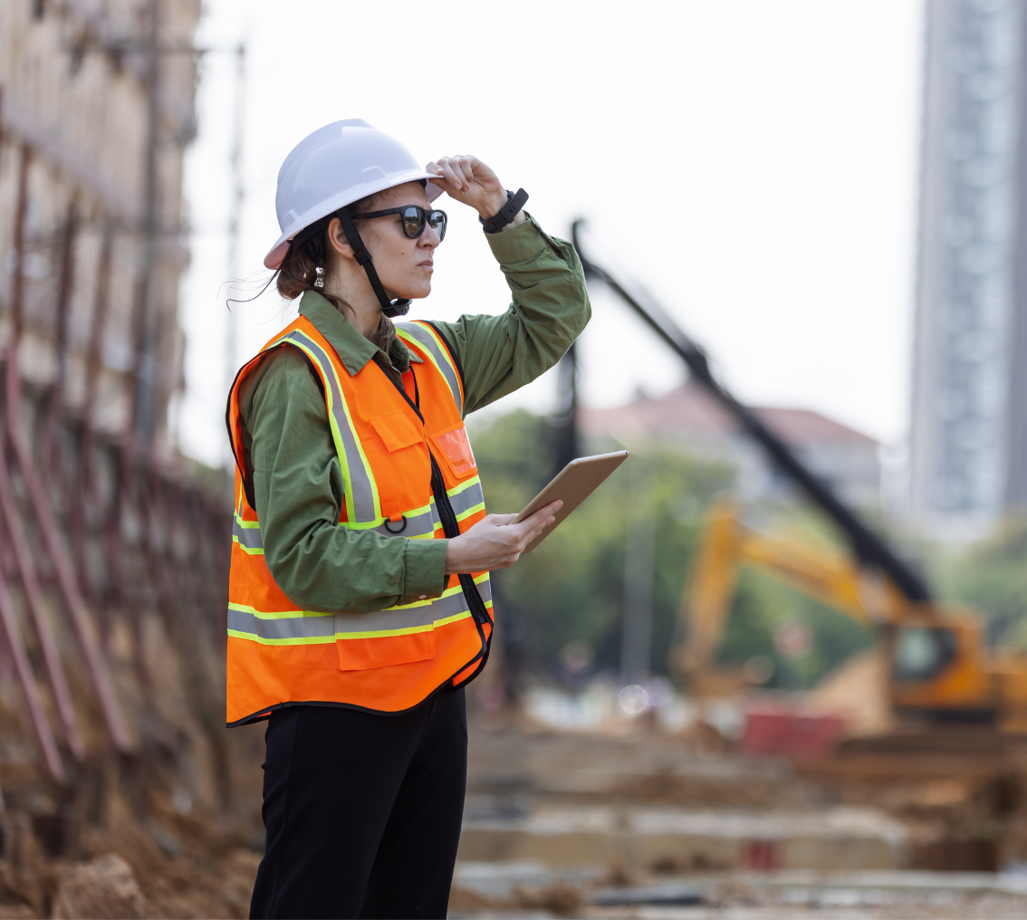 Engenheiro com capacete de proteção e prancheta analisando estrutura predial e industrial